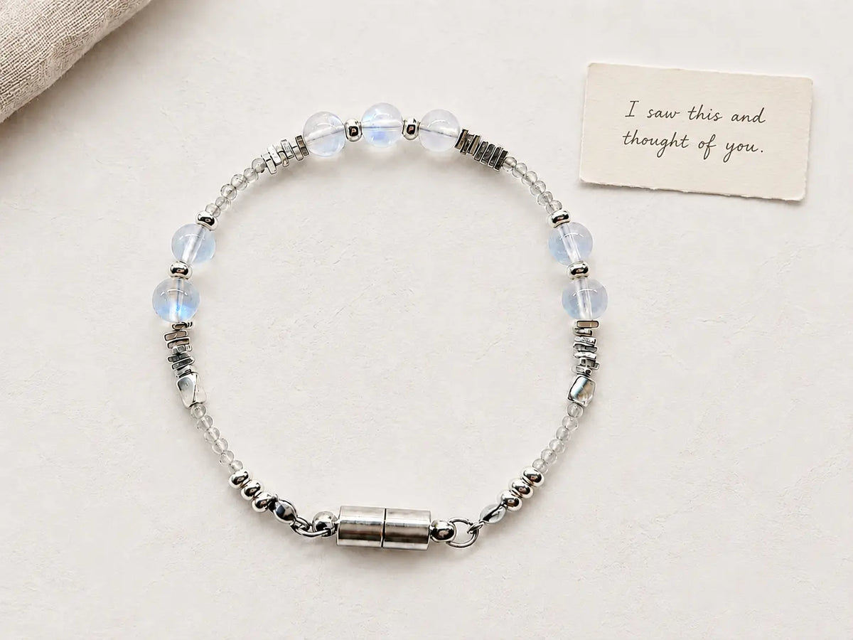 A delicate gemstone bracelet beside a handwritten gift card on a soft neutral surface.