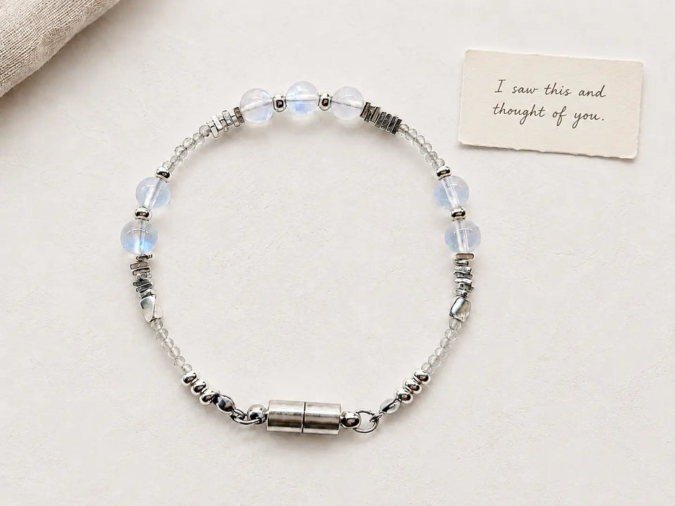 A delicate gemstone bracelet beside a handwritten gift card on a soft neutral surface.