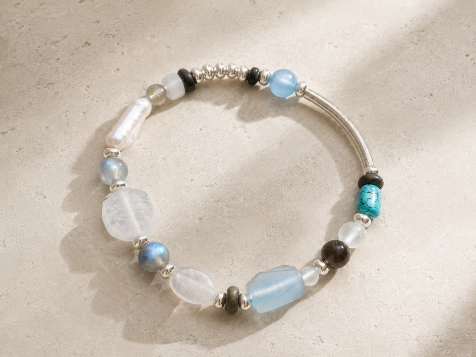 Veiled Light bracelet with moonstone, labradorite, turquoise, pearl, and sterling silver on warm travertine