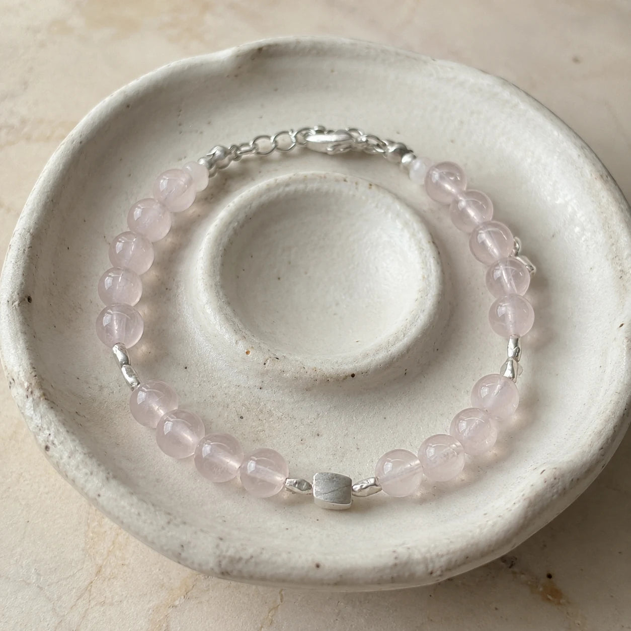 First Blush Poise Bracelet styled on a ceramic dish with rose quartz, white quartz, and silver accents