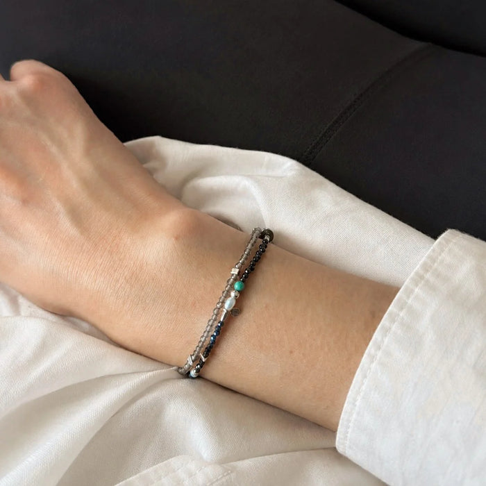 Strata Still Current Bracelet worn on the wrist, showing its fine double-wrap structure and contrasting gemstone accents