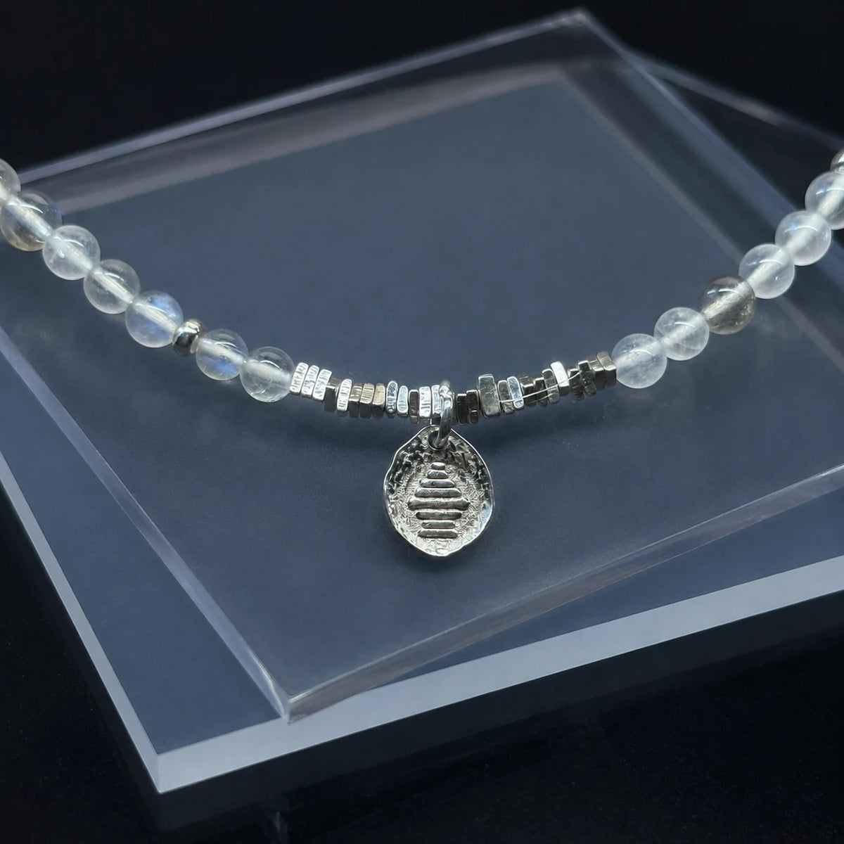 Detail of the Veiled Light Echo Bracelet with 925 sterling silver charm and fine moonstone beadwork
