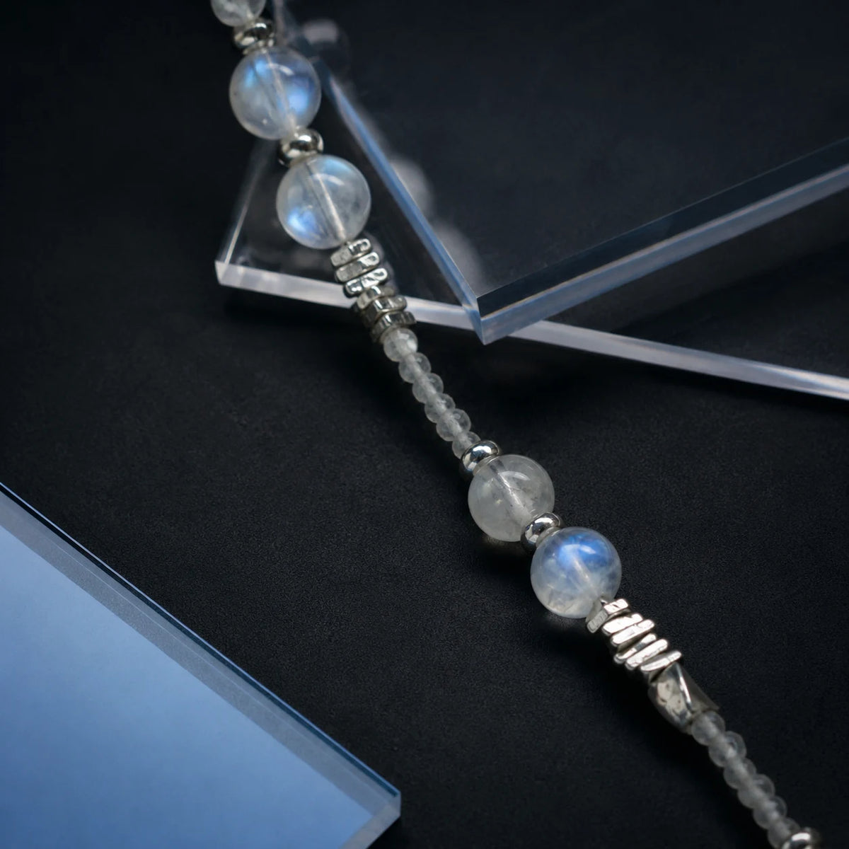 Veiled Light Trace Bracelet styled on a dark surface with moonstone and sterling silver details