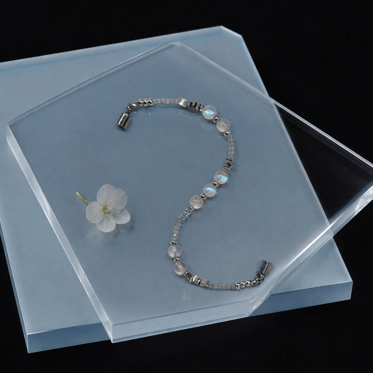 Veiled Light Trace Bracelet arranged on a pale blue display with moonstone and silver accents

5
